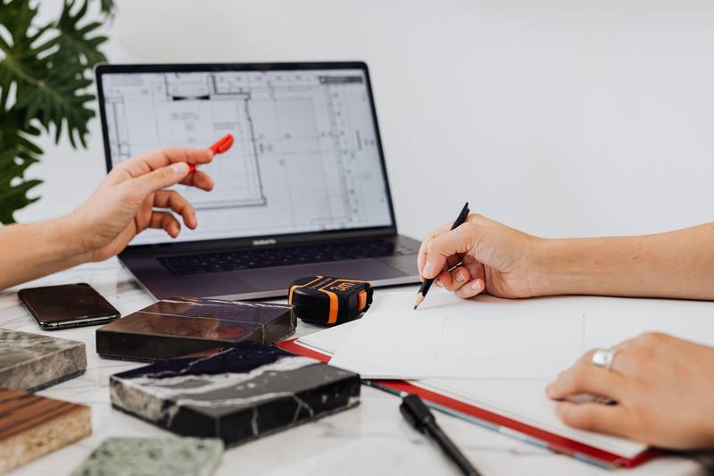 Design sketches with tile samples and a laptop